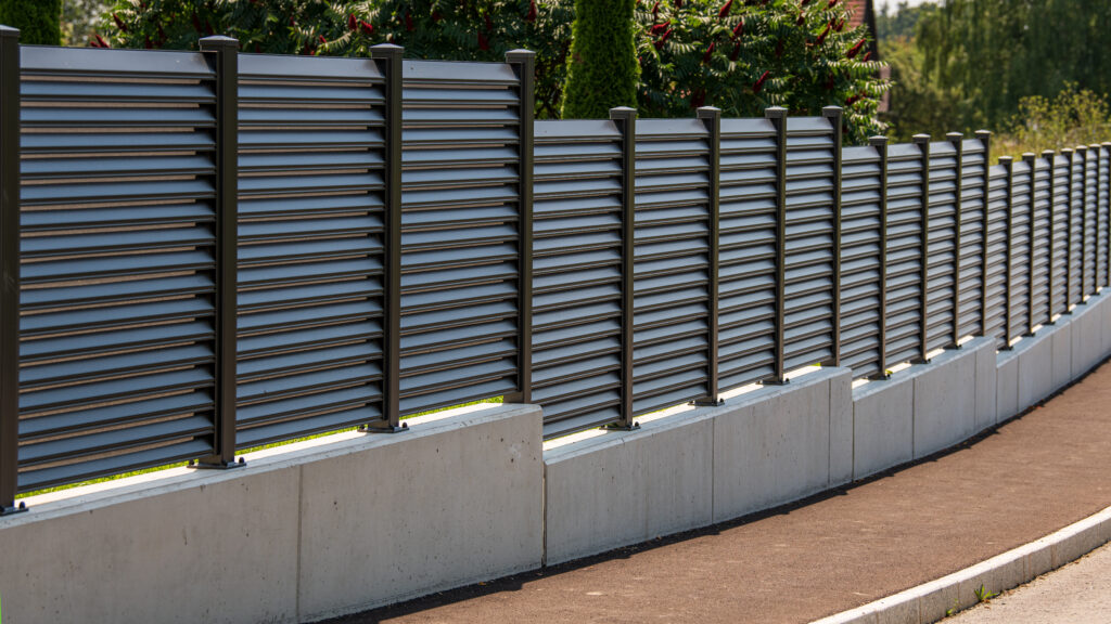 Clôture pare-vue moderne en aluminium sur une rue avec jardin derrière